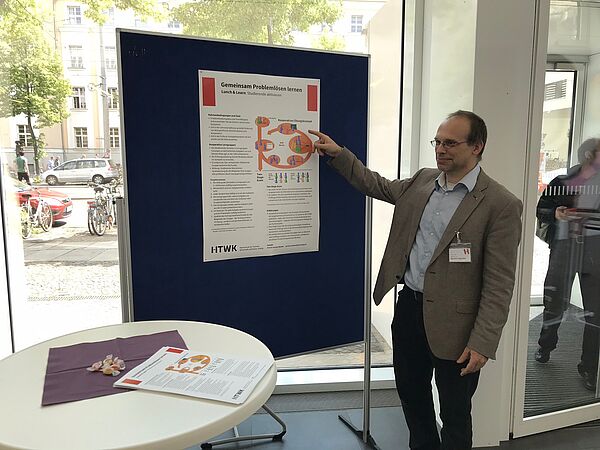 Junger Mann zeigt auf ein Plakat