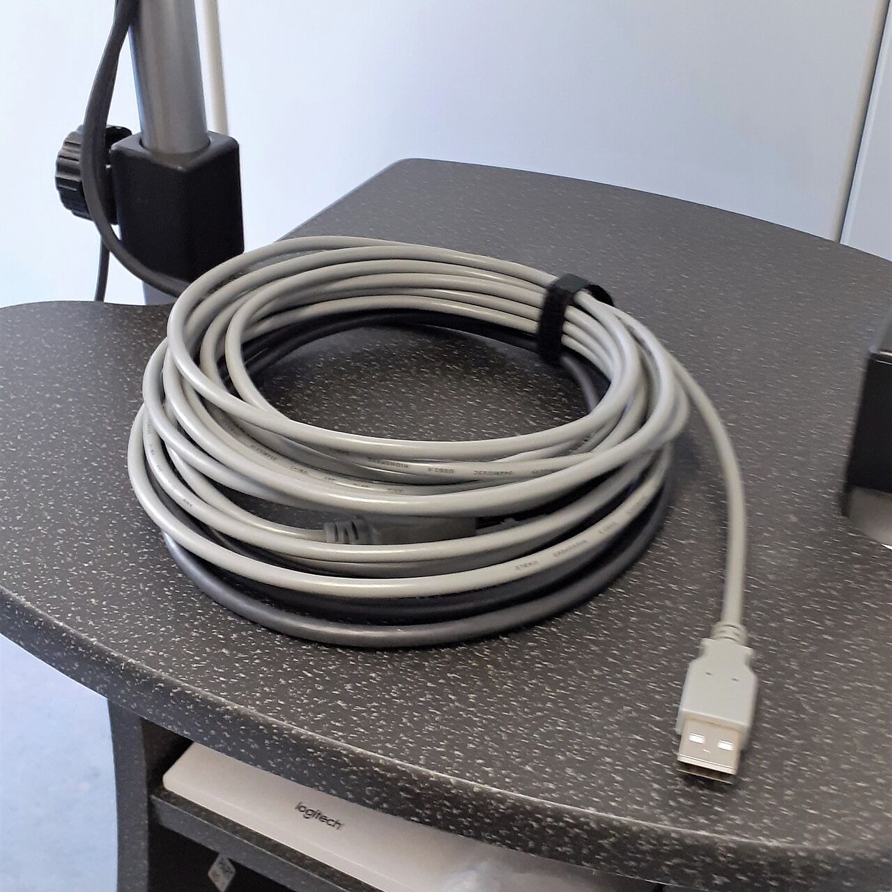 Ein graues USB-Kabel, welches aufgewickelt auf einem Tisch liegt. 