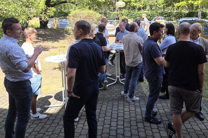 guests are talking and gathering in the garden outside, sun is shining