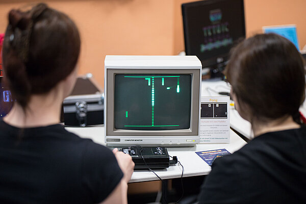Wird in diesem Jahr 50: Das legendäre Videospiel „Pong“ von Atari. Auch dieses Spiel darf bei der diesjährigen Computerspielenacht endlich wieder live und vor Ort gespielt werden. (Foto: Lars Grimmer/HTWK Leipzig) Zwei Personen von hinten vor Computerspiel