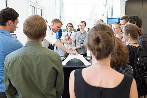 Exponate von FLEX Prof. Alexander Stahr (mittig) demonstriert anhand eines Modells die Statik von Kuppelbauwerken.