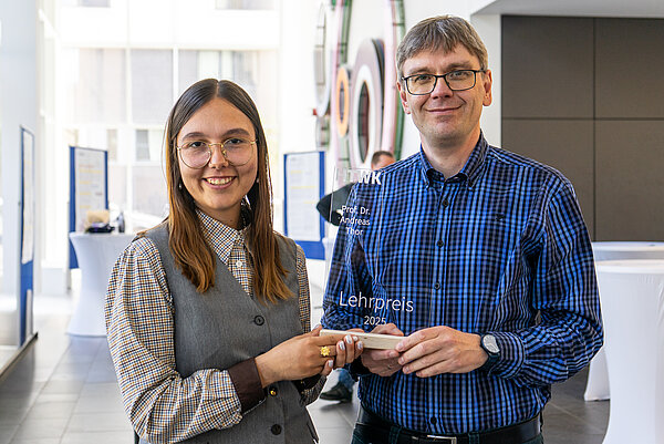 Justyna Daniel und Prof. Andreas Thor (FDIT; Foto: Jan Urban/HTWK Leipzig) zwei Personen lachen, halten Auszeichnung in in die Kamera