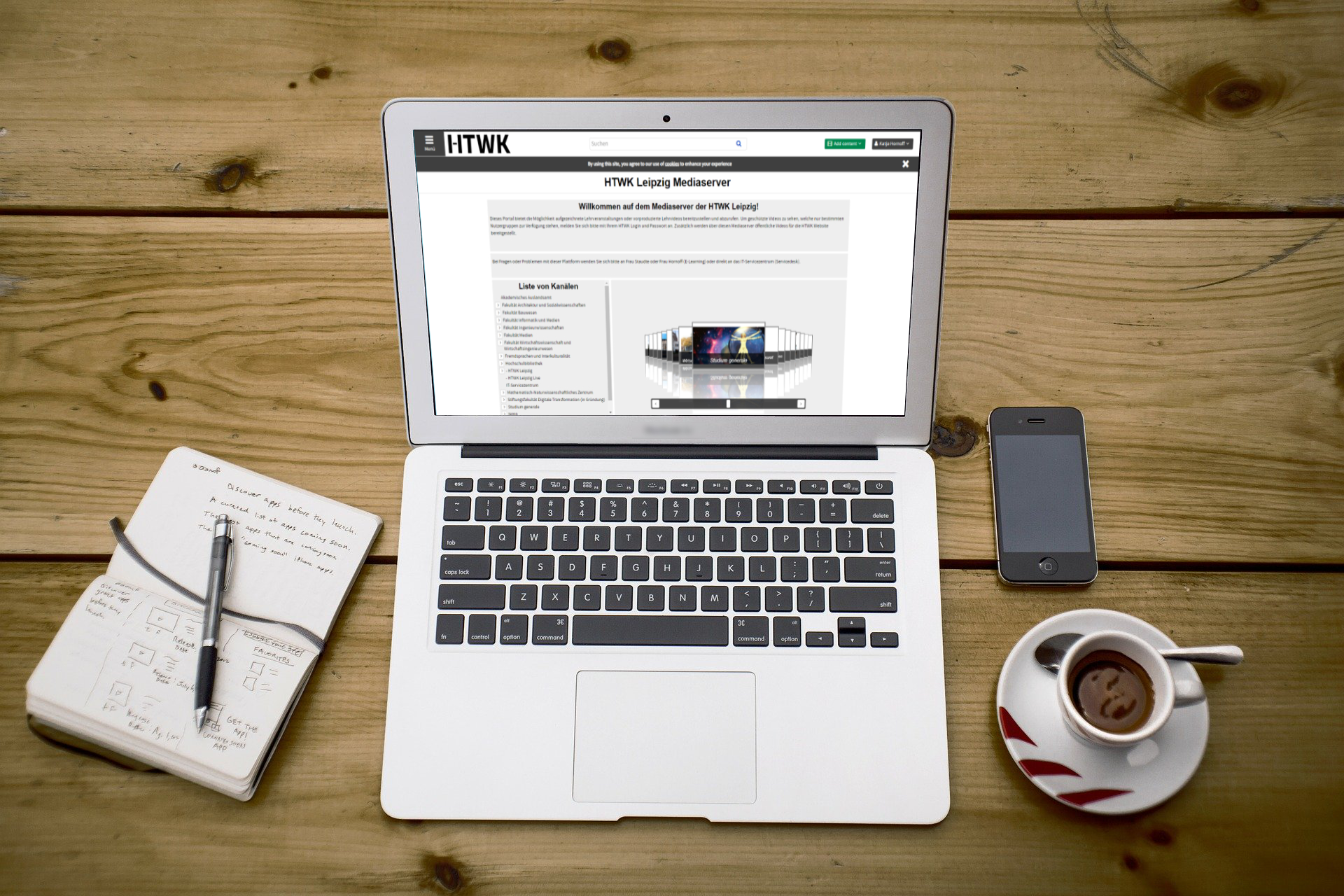 Foto: Notizblock neben offenen Laptop, Smartphone sowie Kaffeetasse